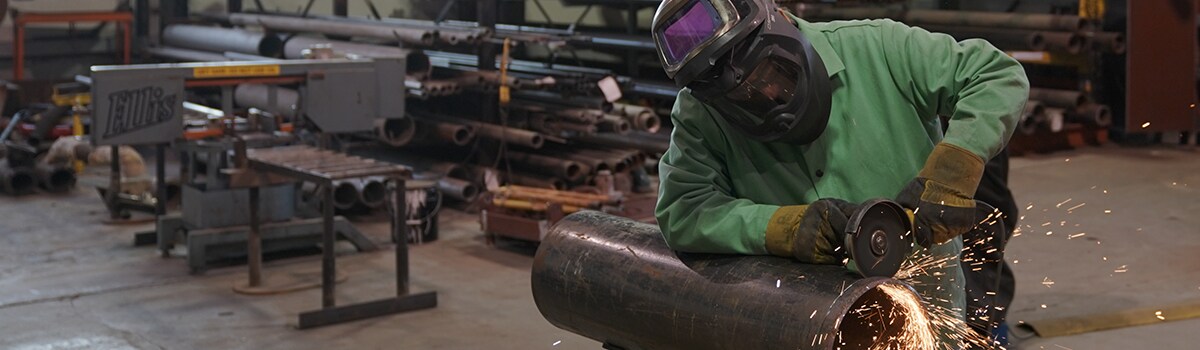 image of person cutting a cylinder with a cutting wheel
